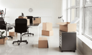 scatoloni accatastati in un ufficio con una sedia con rotelle ed una cassettiera grigia
